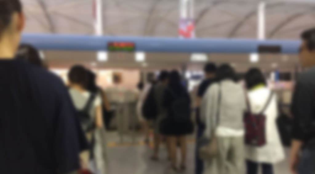 A crowded airport terminal with diverse travelers waiting in line.