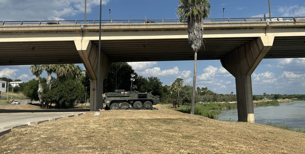 Military vehicle stationed under a bridge at the border for increased security.