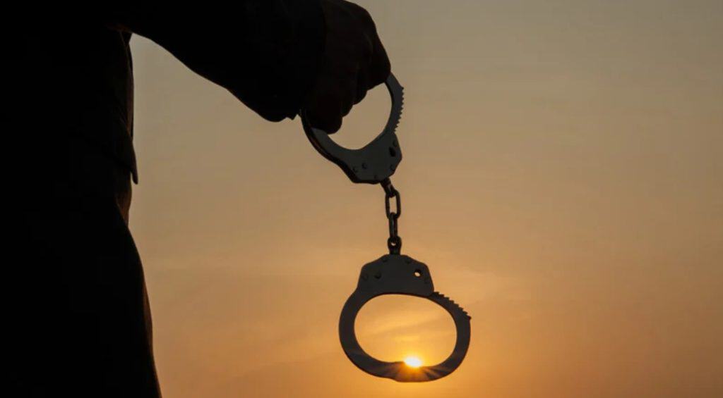 Handcuffs silhouetted against sunset, symbolizing immigration and law enforcement issues.
