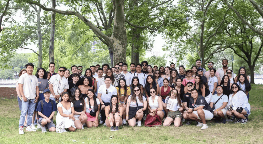 High school students and supporters gather outdoors for a group photo in a park.