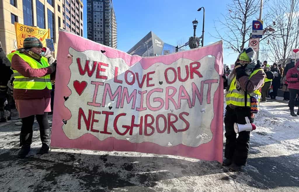 Protesters holding a pink banner that reads "We love our immigrant neighbors" during a rally in Minn.