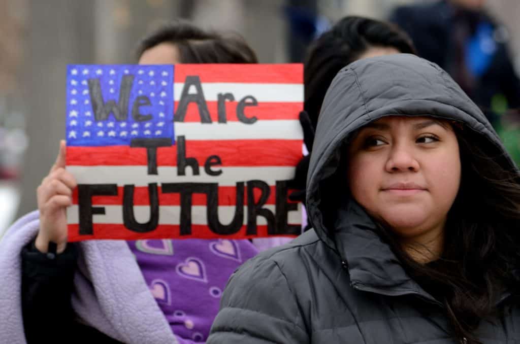 Immigrant youth holding a sign that says "We Are the Future" at a community rally.