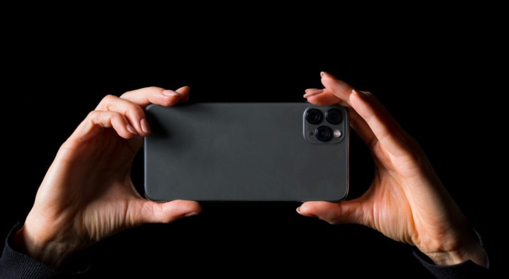 A person holding a smartphone to record or surveil, symbolizing sousveillance and public oversight o.