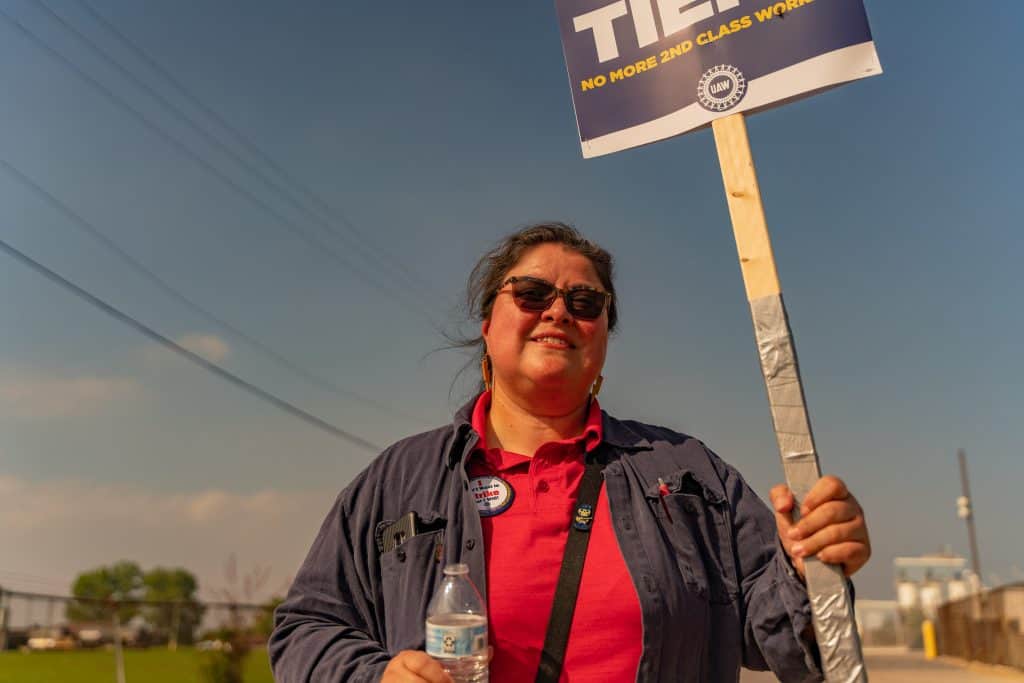 Latino woman protesting for workers' rights in Chicago with a sign.