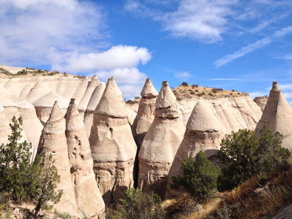 Unique hoodoo rock formations in a desert landscape with blue sky and sparse vegetation.