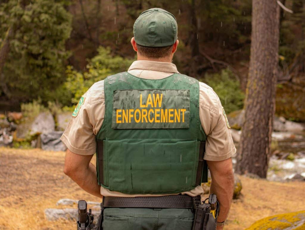 Immigration enforcement officer in a forested area during a crackdown on illegal border crossings.