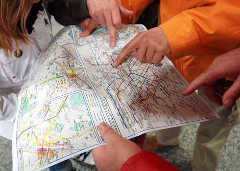 Group of people pointing at a Tokyo subway map, planning their route in Japan's capital city.