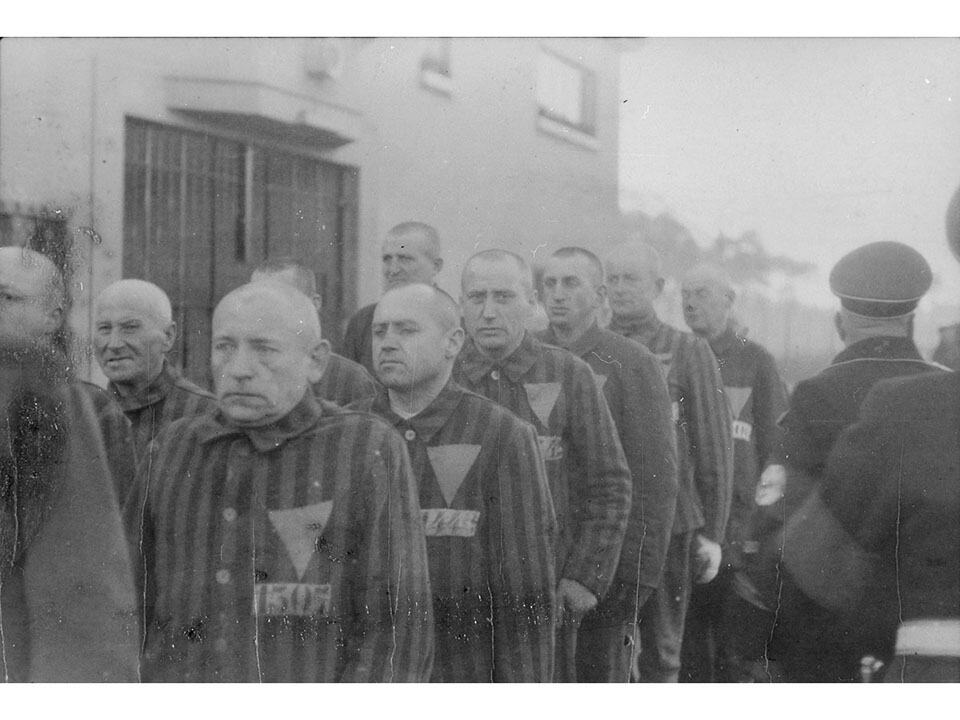 Historical black and white photo of prisoners in striped uniforms during the Holocaust.
