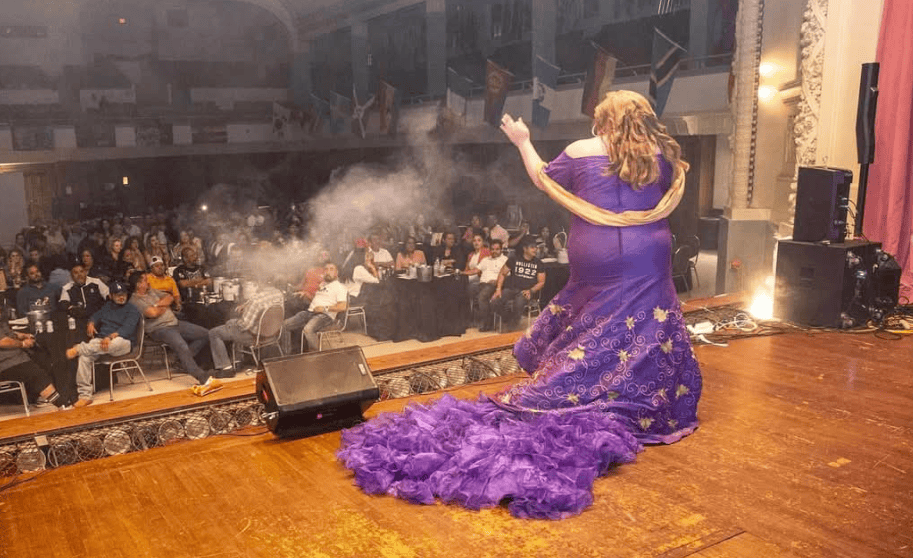 Performer in a purple dress on stage at Latino News Network event.