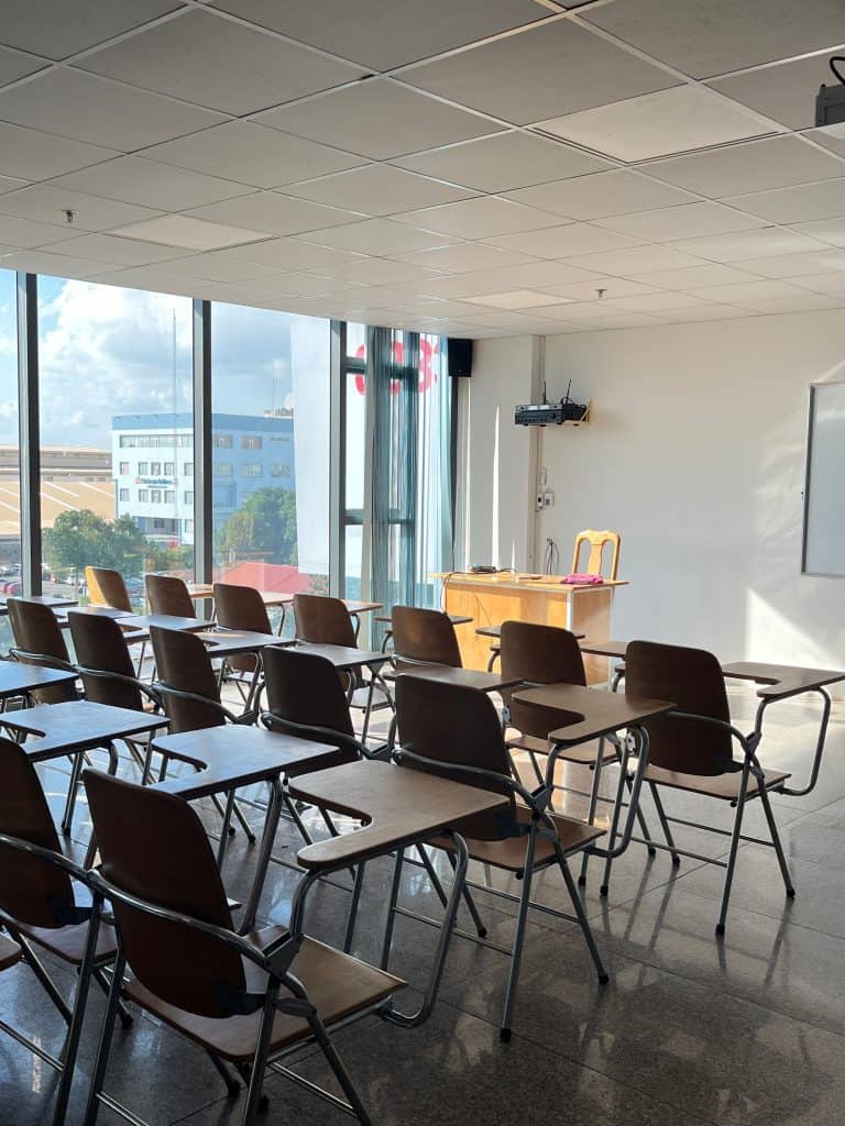 Classroom with large windows, empty chairs, and a whiteboard for educational sessions.