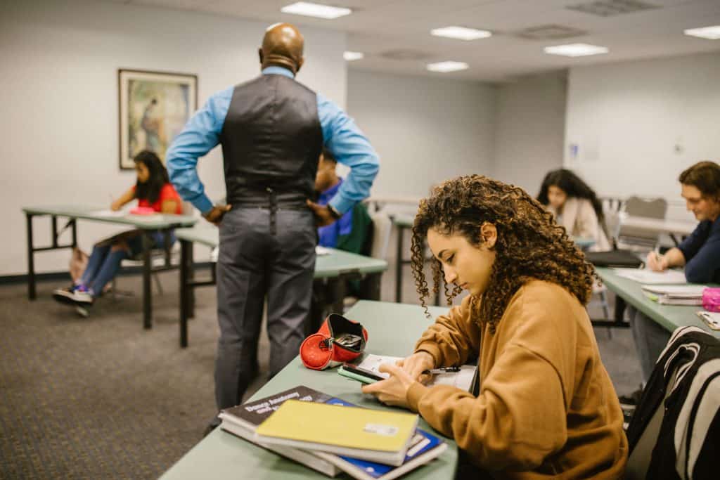 Latino students in classroom with teacher, studying and taking notes.