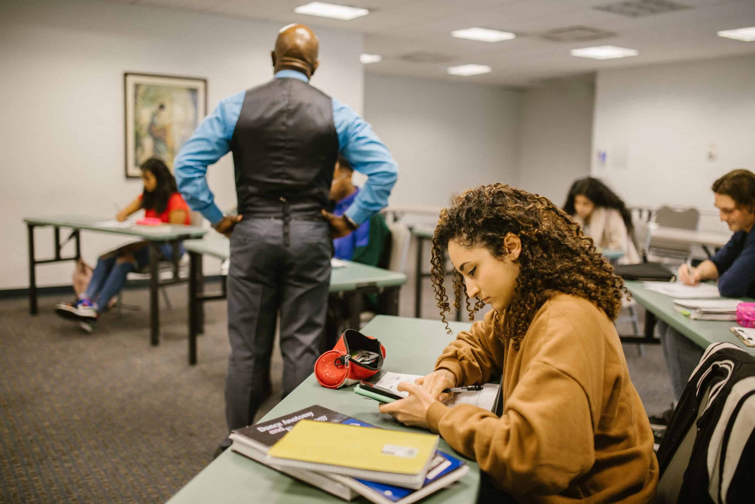 Latino students in classroom with teacher, studying and taking notes.
