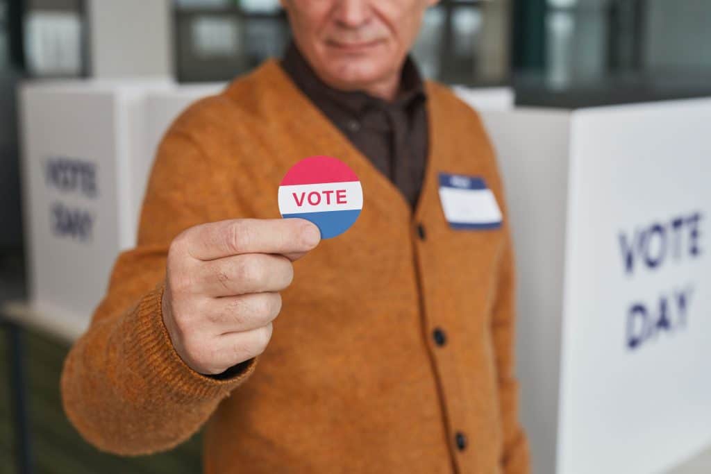 Person holding a 'VOTE' sticker at election polling station.