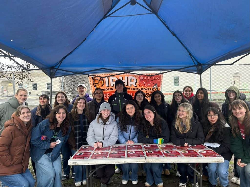 Students gather at a rally advocating for detained immigrants under a blue canopy.