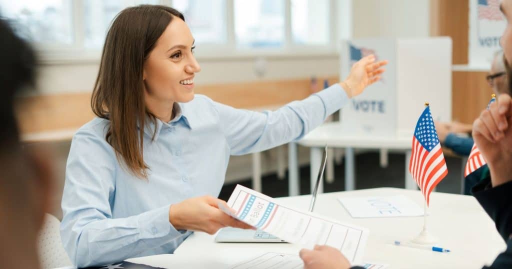 Hispanic young woman encouraging voter participation at a community event.