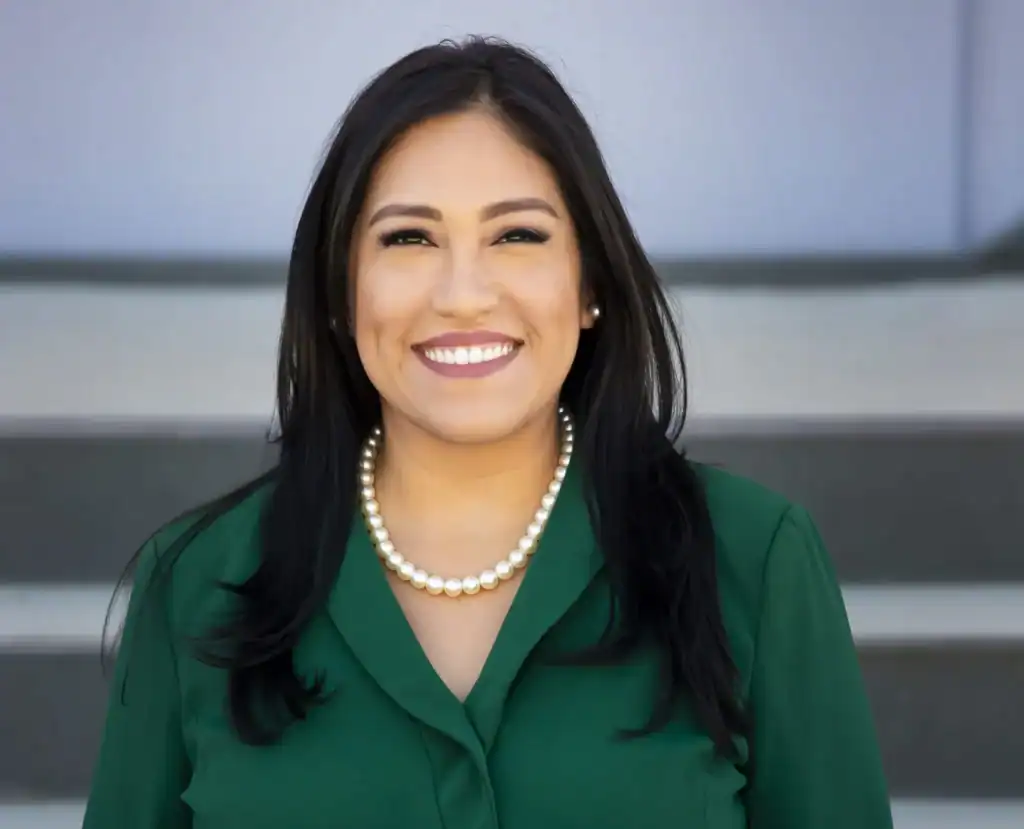 Smiling woman in green blazer with pearl necklace, professional portrait.