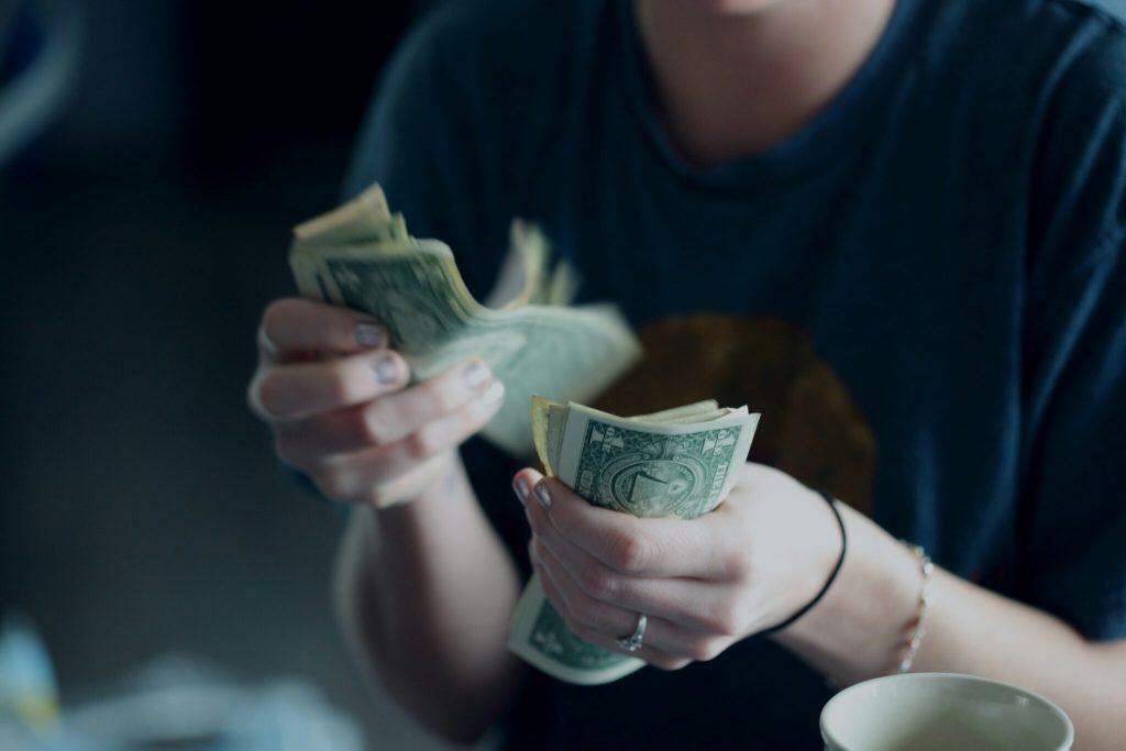 Person counting and handling US dollar bills in a casual setting.