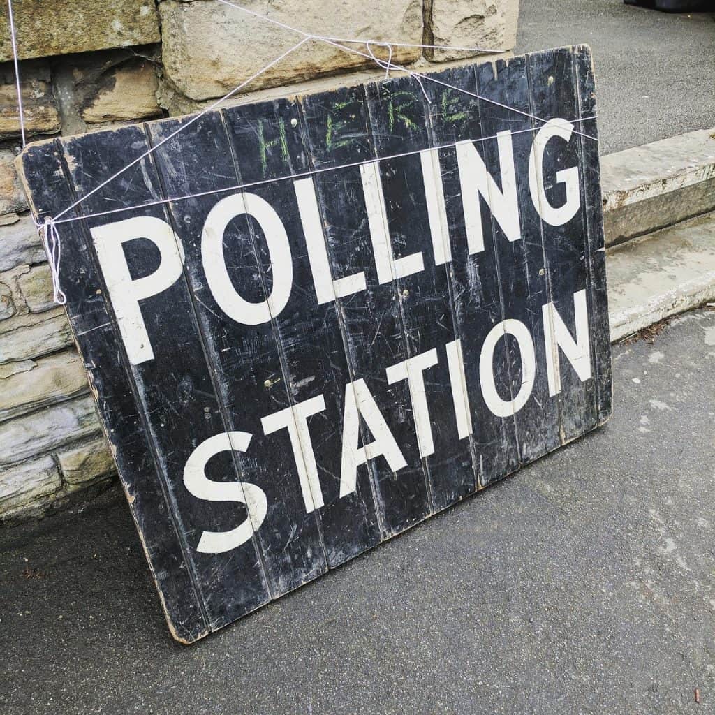 Polling station sign on a sidewalk for voting during elections.