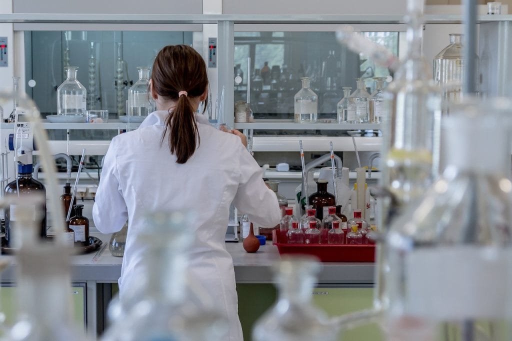 Scientist working in a laboratory with glassware and chemicals.