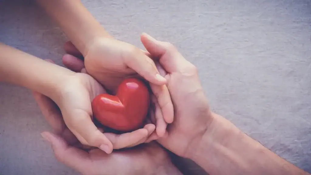 Family members holding a red heart symbolizing care and support for children with rare diseases.