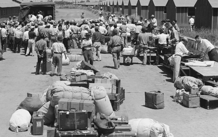 Historical migrant camp with people unloading luggage and supplies.