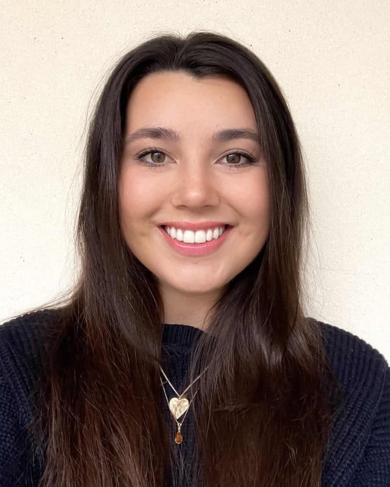 download (1) Smiling young woman with long dark hair wearing a navy sweater.