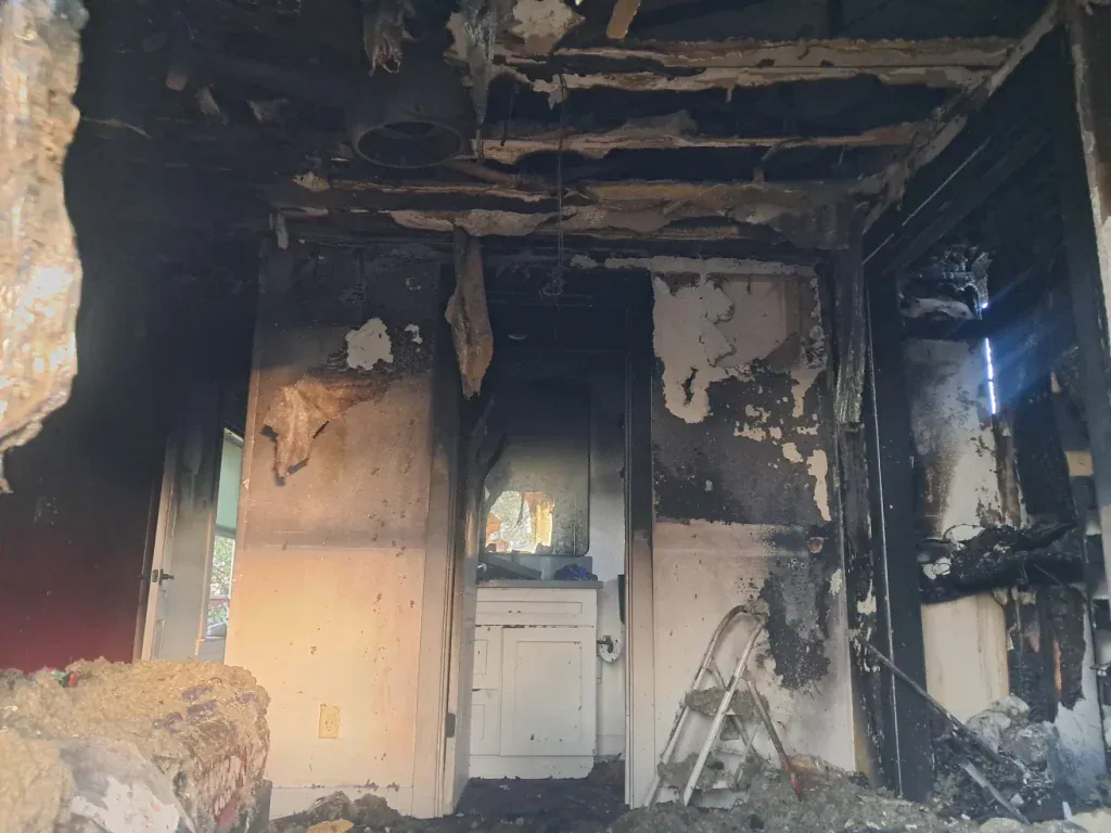 Burned interior of a house after fire damage, showing charred walls and ceiling.