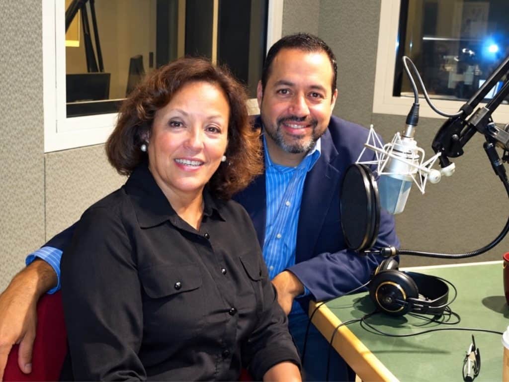 download (3) Latino News Network hosts in a recording studio with microphone and headphones.