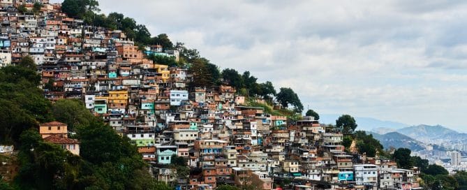 Colorful hillside neighborhood with dense housing on a slope under a cloudy sky.