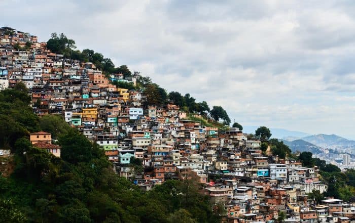 Colorful hillside neighborhood with dense housing on a slope under a cloudy sky.