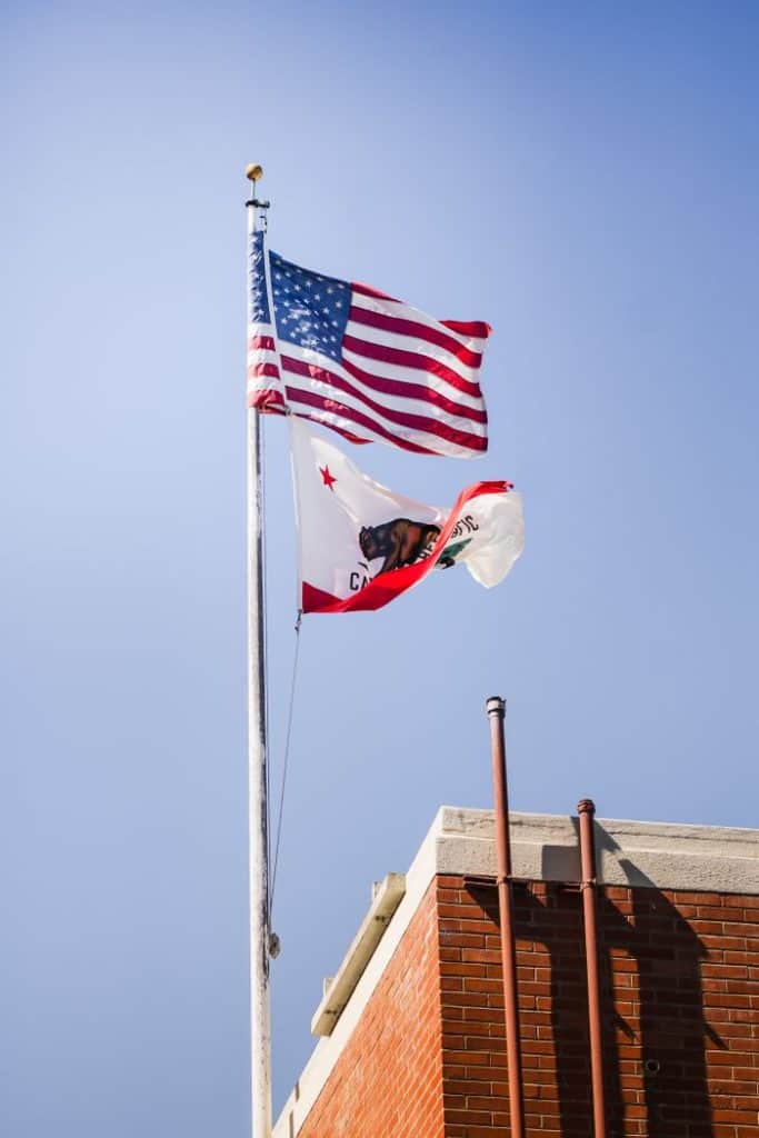 American and California flags flying on a clear day.