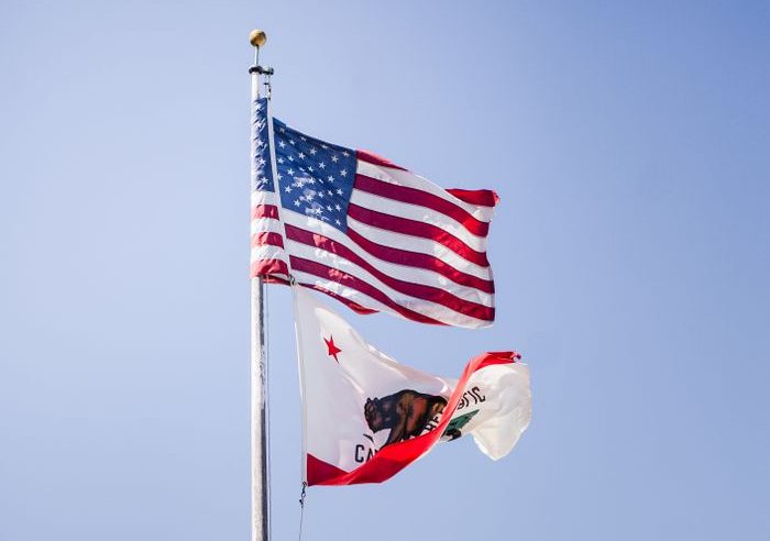 American and California flags flying on a clear day.