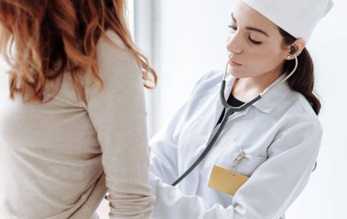 Medical professional using stethoscope on patient in clinical setting.