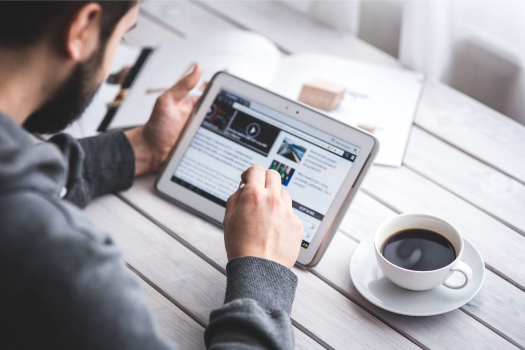Person using tablet to access news on democracy and solutions journalism.