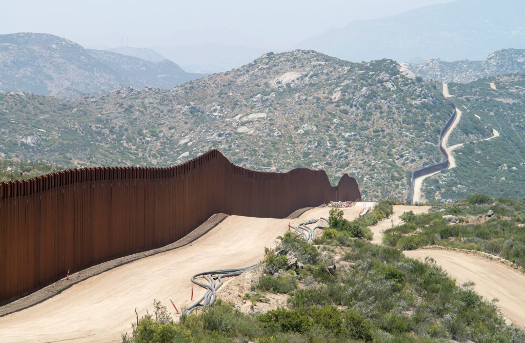 Border wall along the U.S.-Mexico border in a mountainous region.