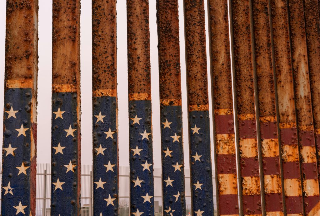 Close-up of a rusty iron fence painted with stars and stripes at the American-Mexican border in Tijuana.