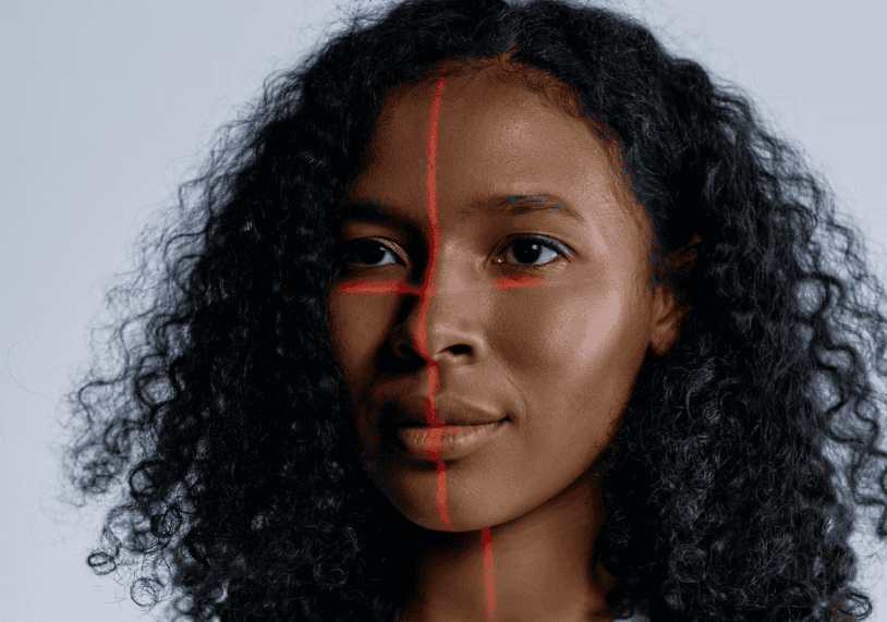 Close-up of a woman's face with red laser lines crossing it.