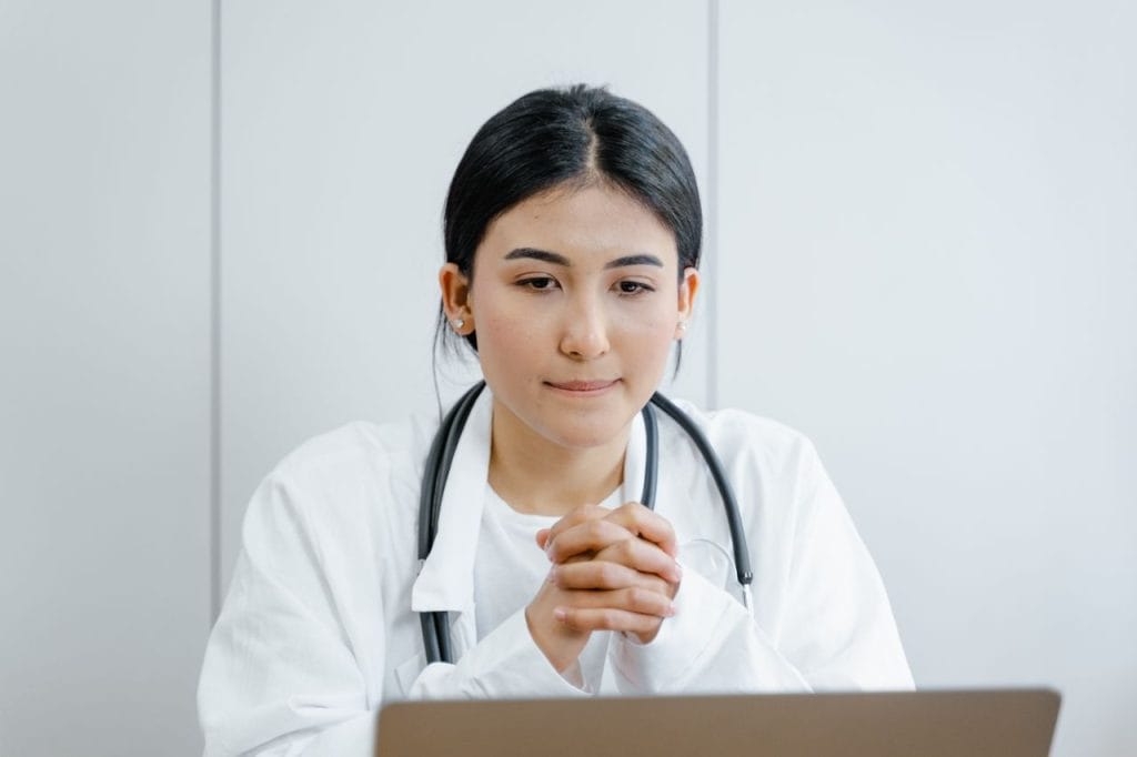 Latino healthcare professional with stethoscope at desk.