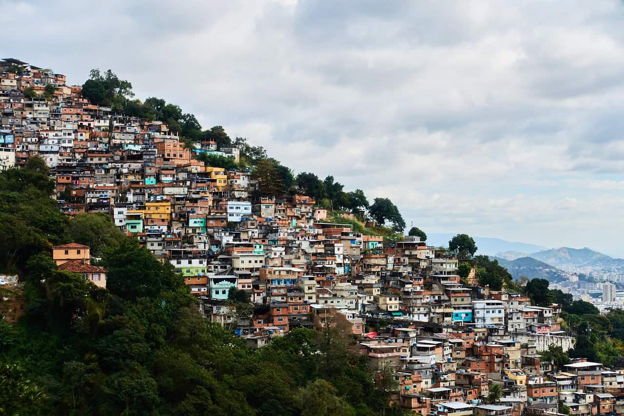 Colorful hillside neighborhood with dense housing on a slope under a cloudy sky.